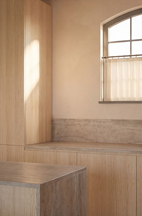 Bespoke oak kitchen cabinetry and stone-effect worktops positioned beneath an arched steel-framed window.
