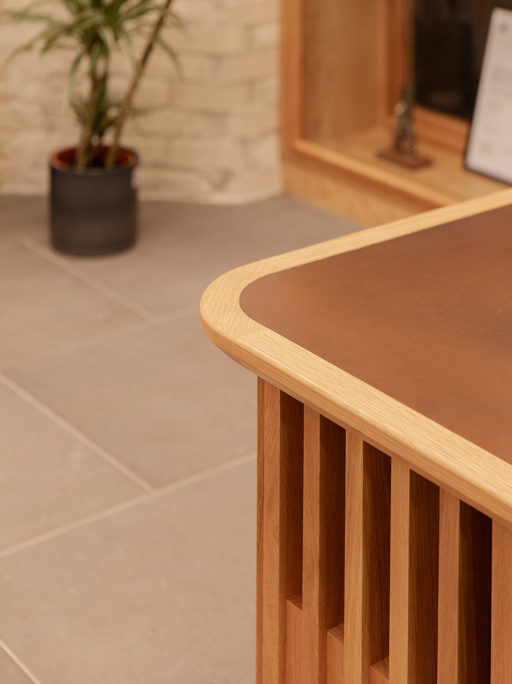Curved timber reception desk with vertical oak slats and integrated work surface within the reception atrium.