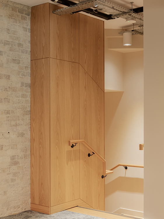 New staircase connecting two levels of the workplace, featuring timber treads, exposed brick walls and timber balustrades.