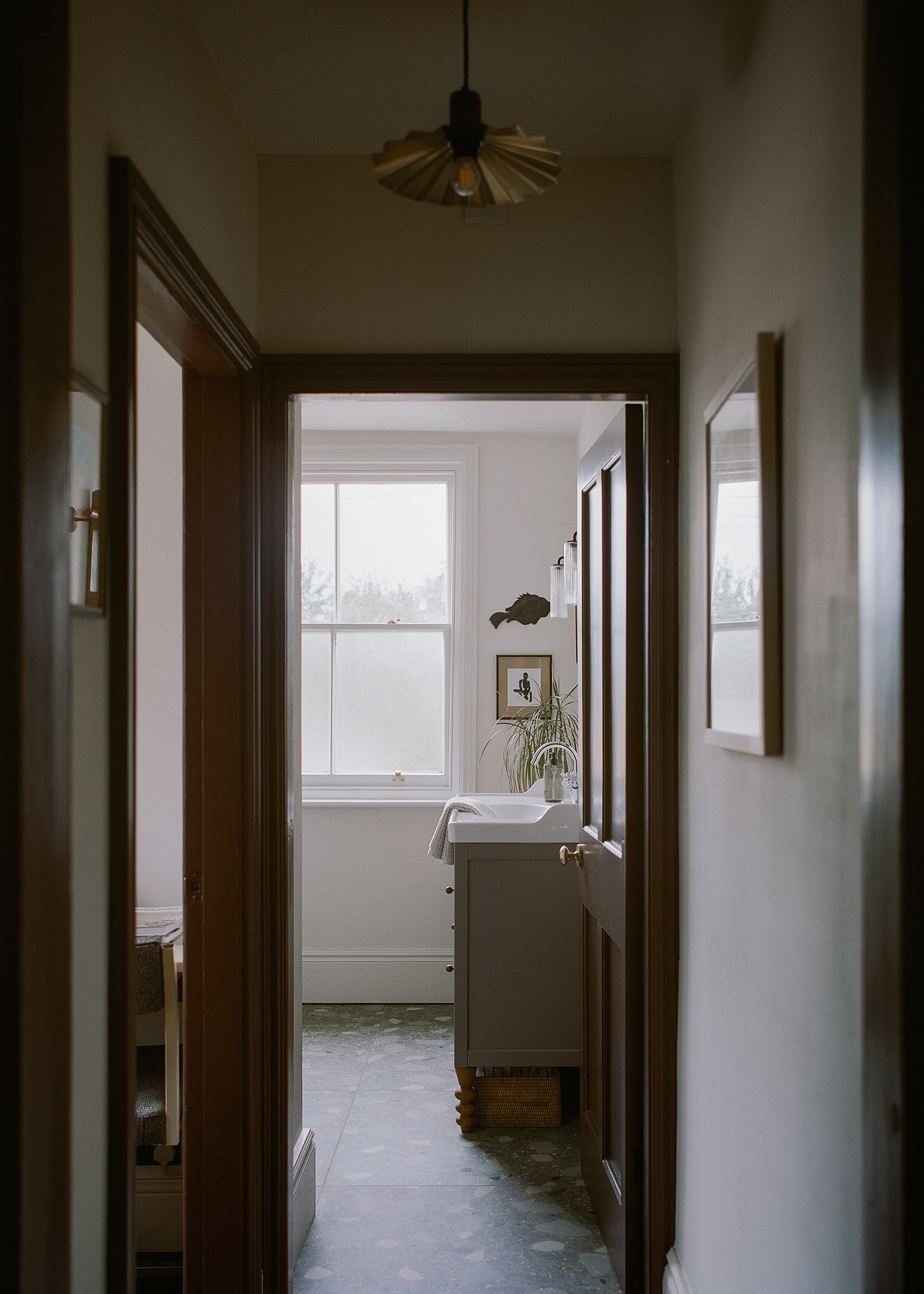 View along hallway towards bathroom with terrazzo flooring, traditional joinery and natural light.