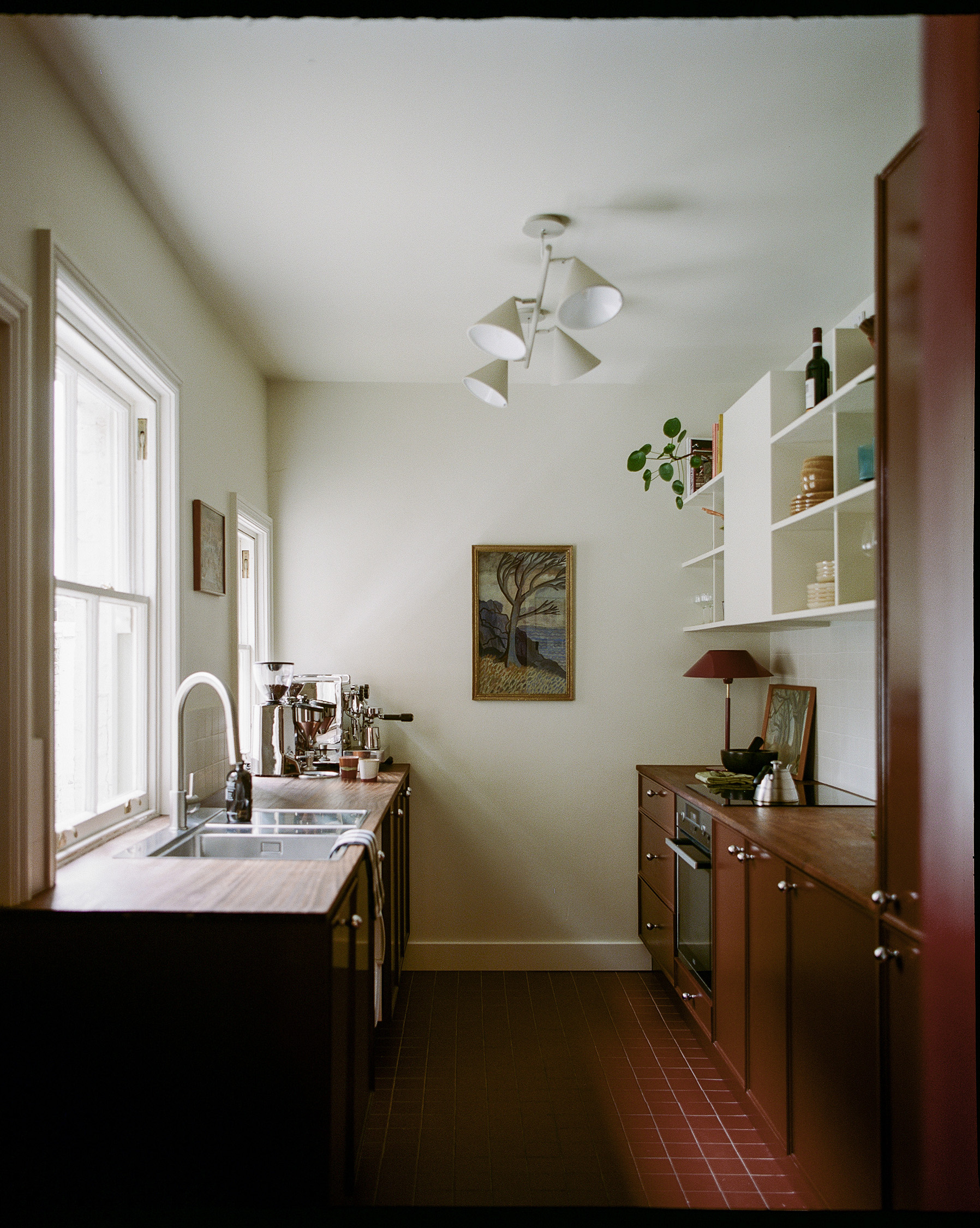 View through kitchen doorway showing bespoke cabinetry, open shelving and retained period proportions.