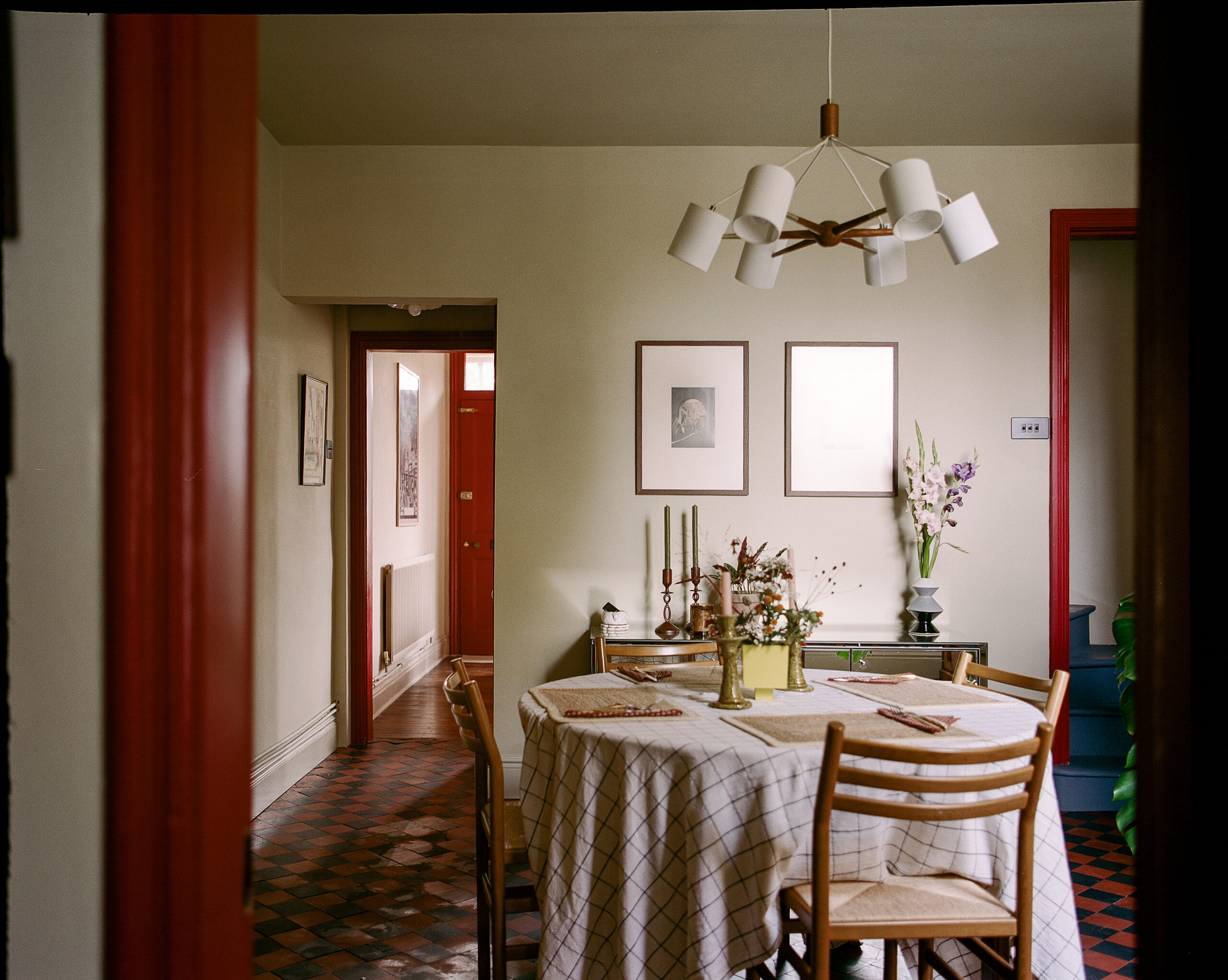 Dining room with checkerboard tiled floor, timber furniture and soft yellow walls.