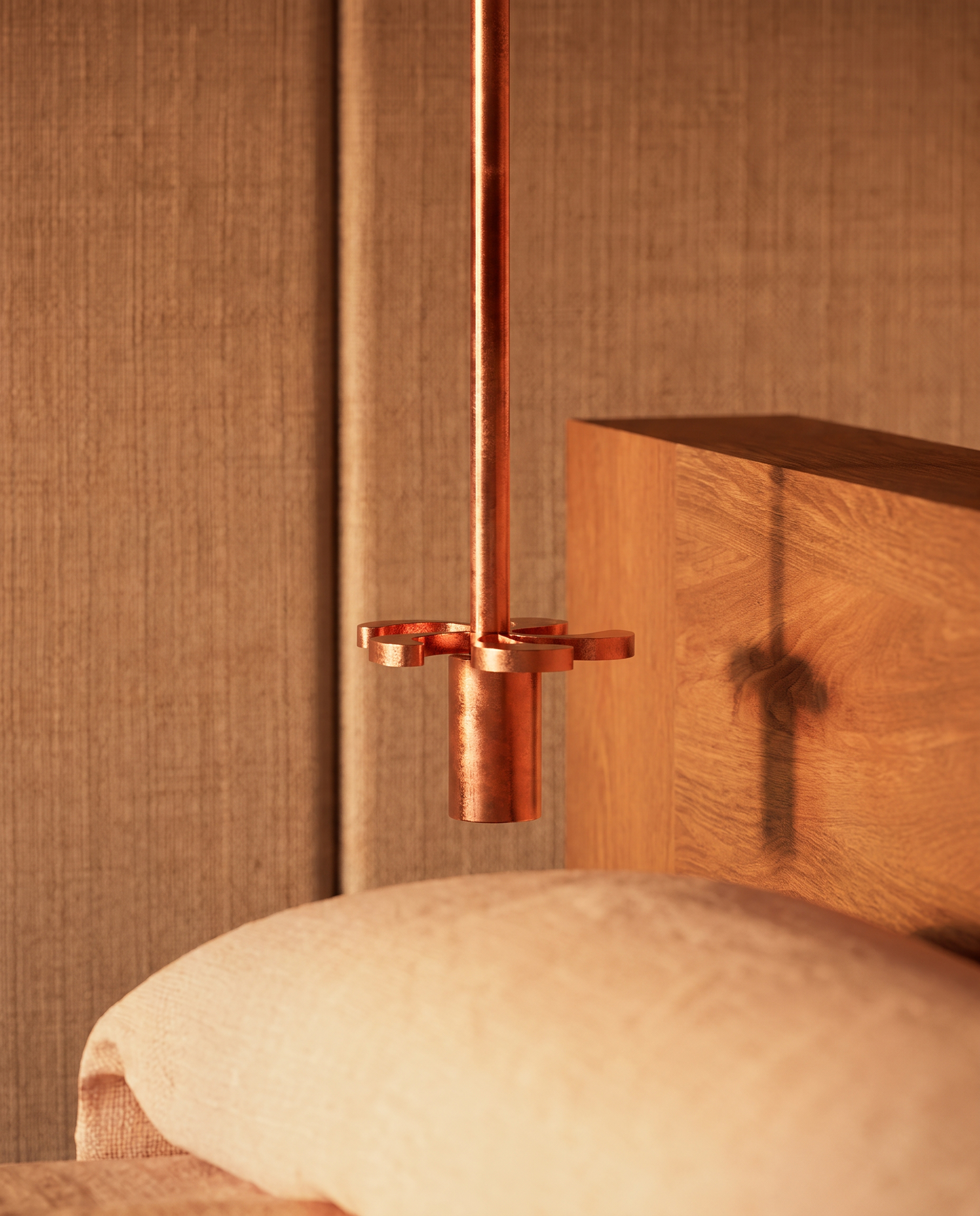 Close-up of a sculptural copper bedside light beside a timber headboard and upholstered bed